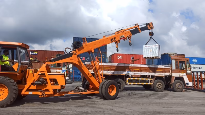 A mobile crane loading palletised cargo onto a truck at the container yard