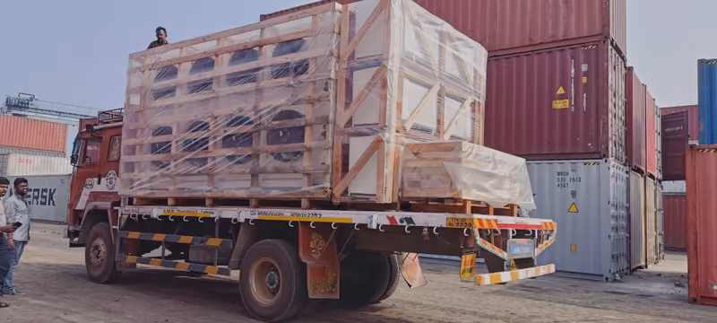 Crated equipment strapped on a flatbed truck leaving the container yard